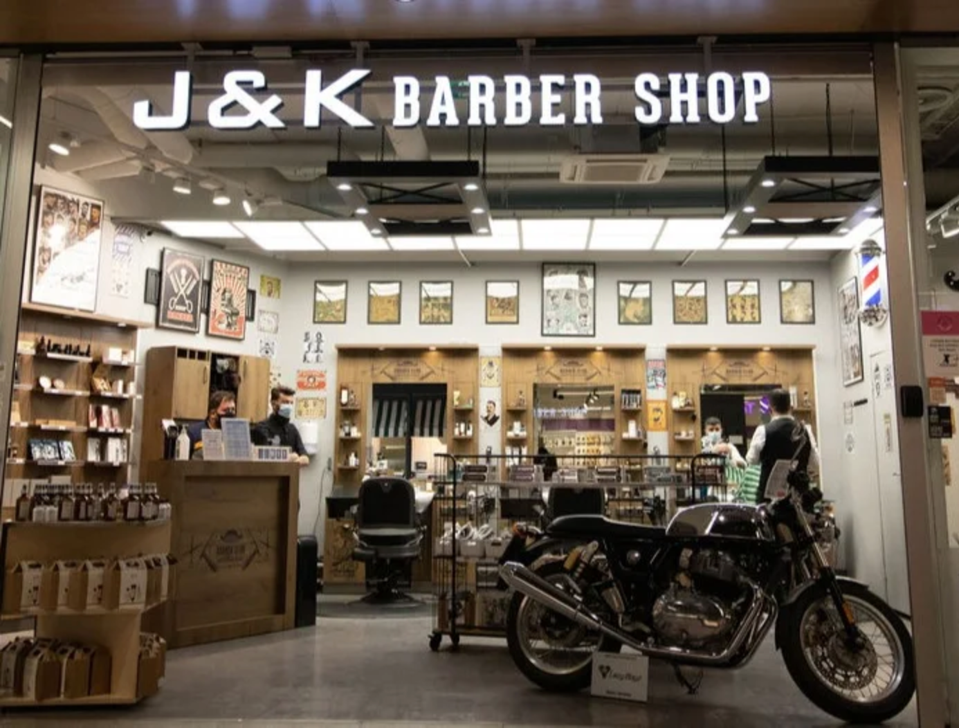 Interior of J&K Barber Shop with motorcycle display, professional barber chairs, and shelves of grooming products.