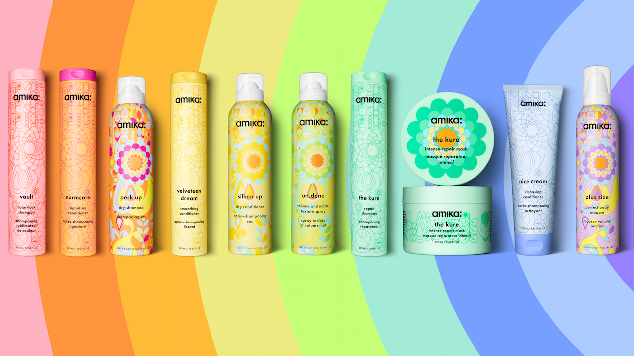 Colorful amika hair care product lineup with various bottles and containers against a vibrant rainbow background.